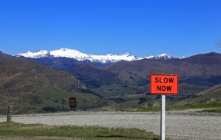 A line of snowy mountain tops with a sign that reads 'Slow Now'